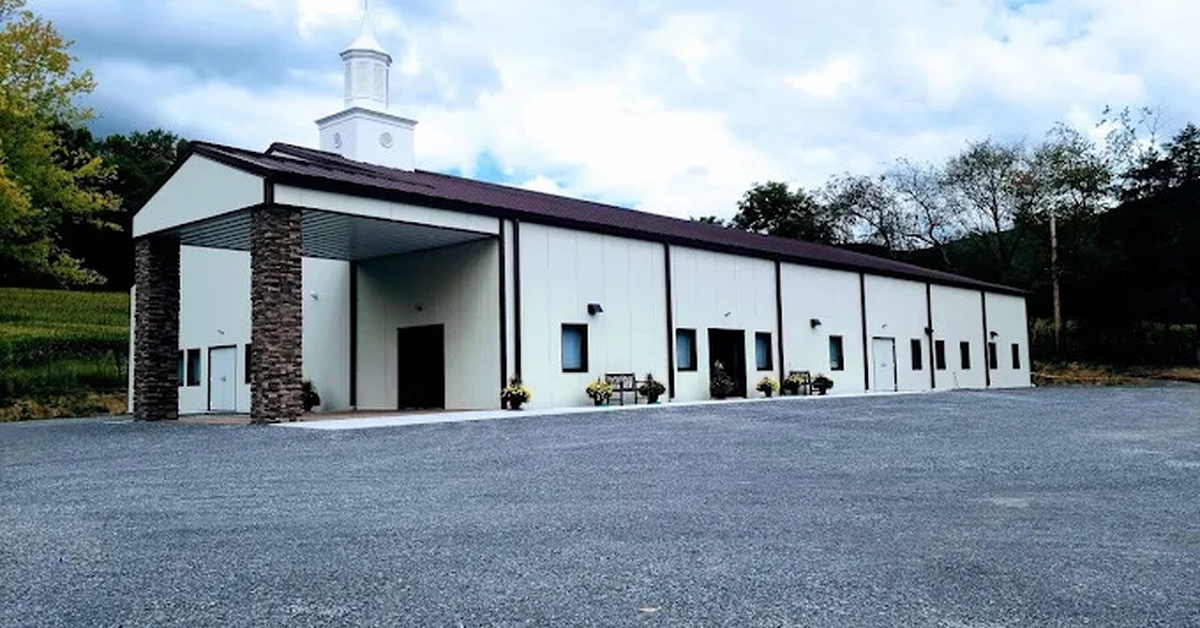 The outside of a church building. The entrance has stone pillars and the roof has a small steeple emerging from it.