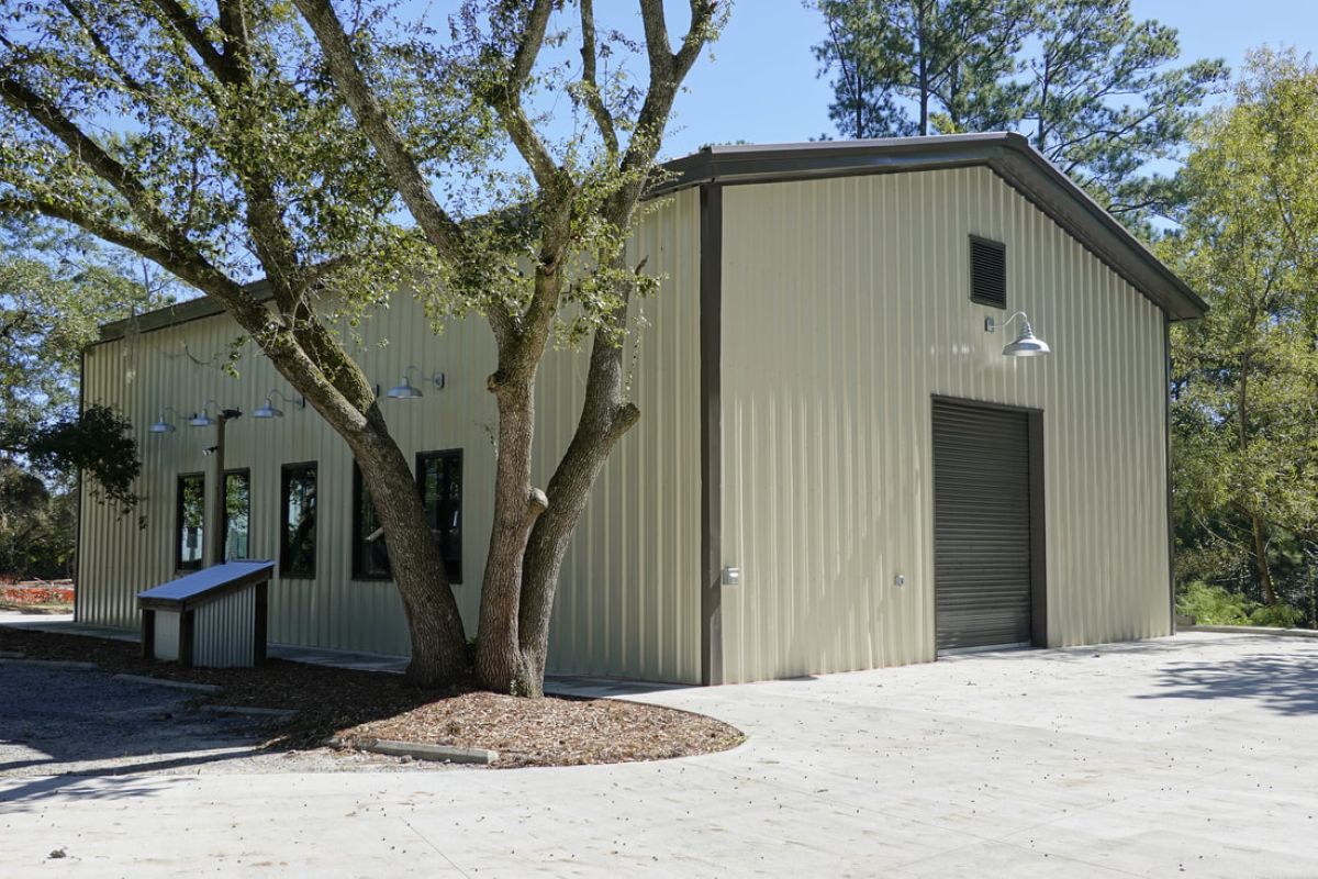 The exterior of a small warehouse building. The front of the building has a roll-up door to allow for vehicle access.